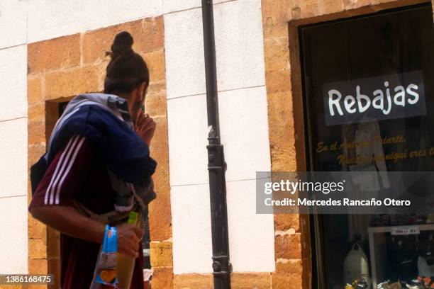 young woman looking at a sales sign on a window clothing store. - rebajas 個照片及圖片檔