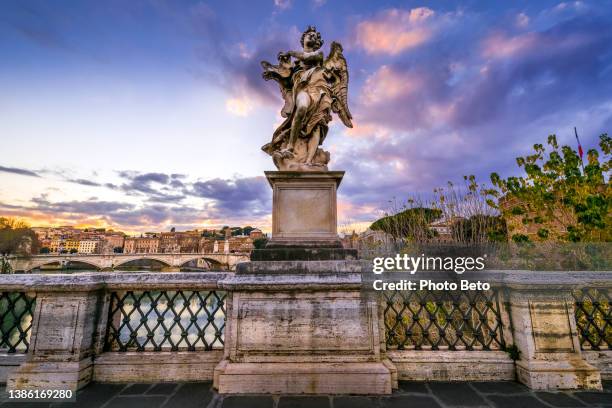 la luce del tramonto avvolge una statua della bottega del bernini lungo ponte sant'angelo nel cuore barocco di roma - balustrade foto e immagini stock