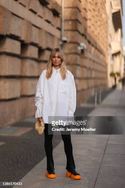 Nadine Berneis wearing a white oversize blouse, black pants, a Bottega Veneta mini beige Jodie leather bag and Bottega Veneta black and orange...