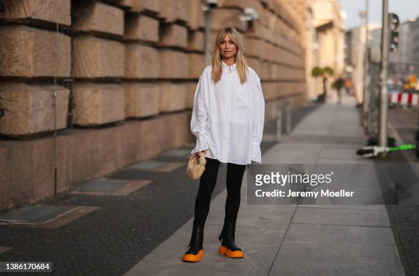 Nadine Berneis wearing a white oversize blouse, black pants, a Bottega Veneta mini beige Jodie leather bag and Bottega Veneta black and orange...