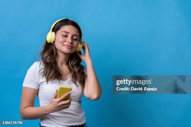 relaxed woman enjoying listening to music with a smartphone and headphones over an isolated background. - headphones isolated ストックフォトと画像