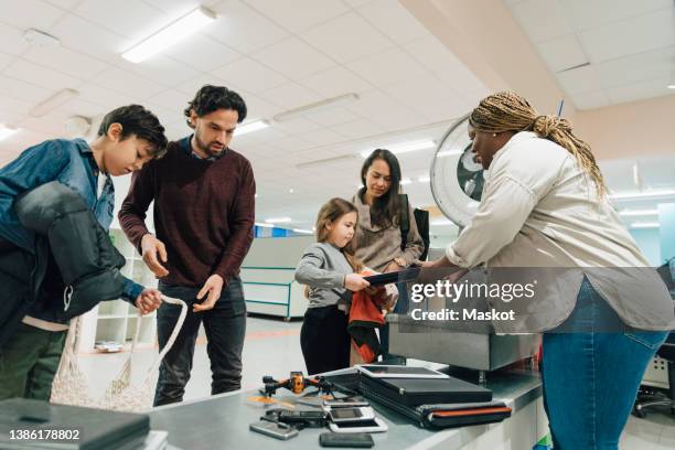 children with parents exchanging electronics at counter in recycling center - recycling center photos et images de collection