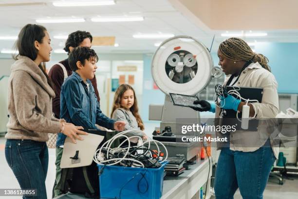 female worker examining digital tablet by customers at electronics industry - e waste stock pictures, royalty-free photos & images