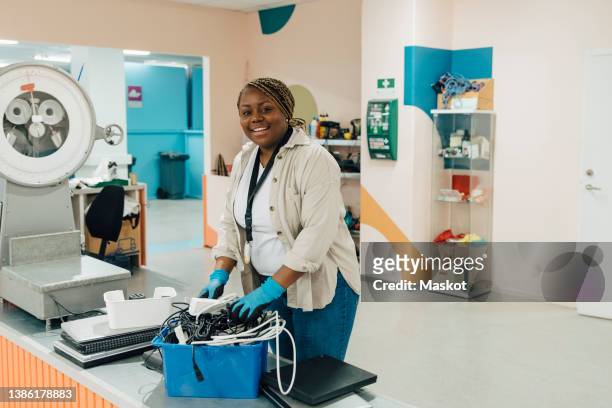 smiling female worker with cables in box at electronics industry - elektronisch afval stockfoto's en -beelden