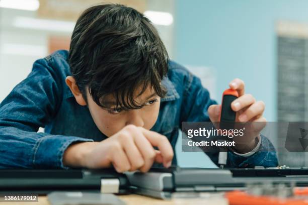 boy repairing laptop in recycling center - recycling center stockfoto's en -beelden