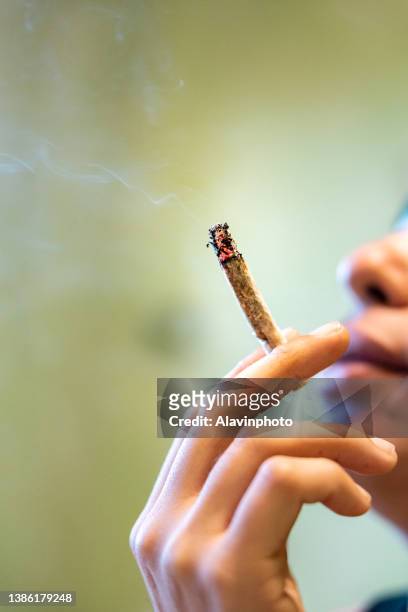teenager smoking a joint of marijuana drug - hanfpflanze stock-fotos und bilder