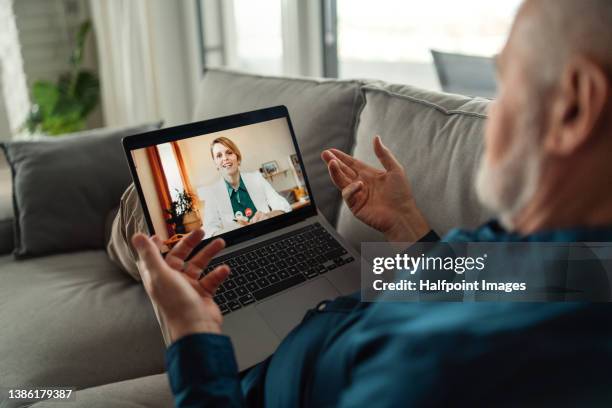 senior man sitting on sofa and having video call with his doctor. - doctor and patient talking imagens e fotografias de stock