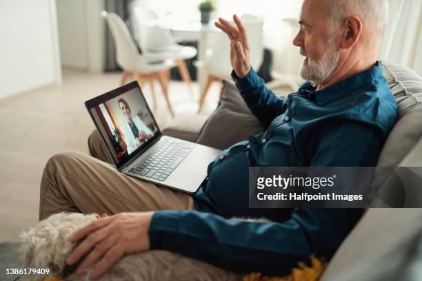 senior man sitting on sofa and having video call with his doctor. - doctor house call stock pictures, royalty-free photos & images