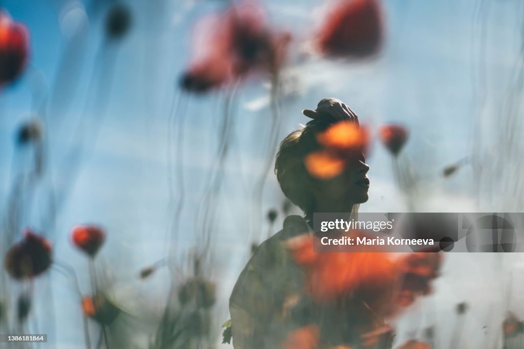 Dreamy portrait of a young woman in poppy field.