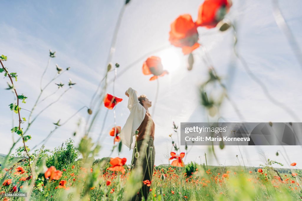 Dreamy portrait of a young woman in poppy field.