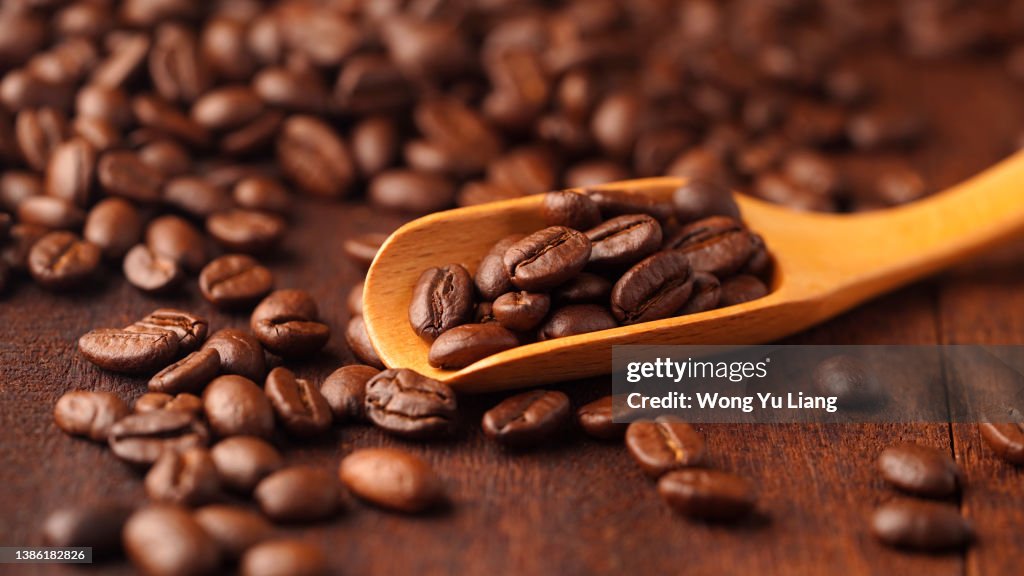 Coffee bean on wooden spoon , with wood background