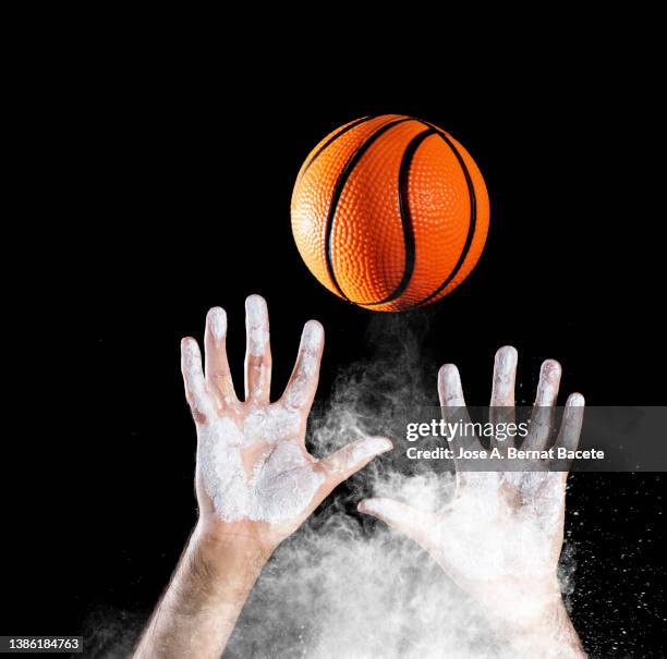 hands of a basketball player catching a ball on a black background. - ballon rebond stock-fotos und bilder