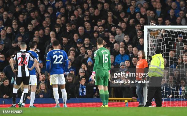 Players from both sides look on as a protestor ties himself to the post during the Premier League match between Everton and Newcastle United at...