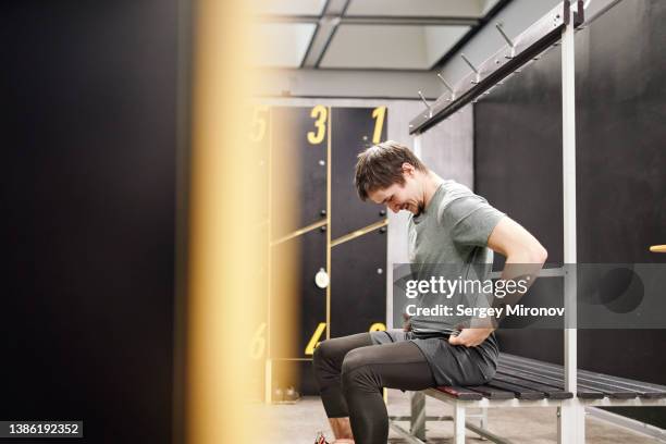 smiling sportsman putting on t shirt in gym - mens changing room stock pictures, royalty-free photos & images