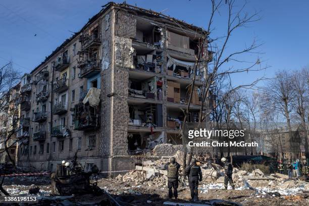 Police and military personnel stand in front of a residential apartment complex that was heavily damaged by a Russian attack on March 18, 2022 in...