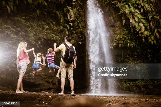 rückansicht einer familie, die spaß am wasserfall in der natur hat. - behind waterfall stock-fotos und bilder