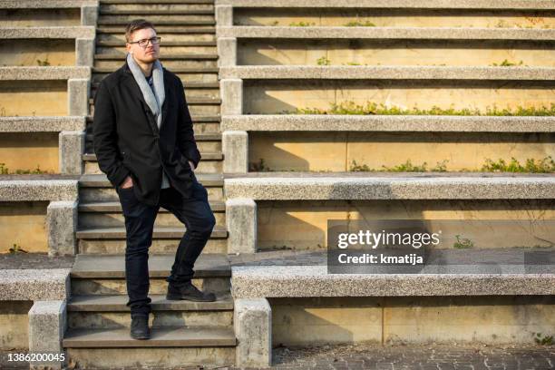 well-dressed young man walking down a staircase outdoors - northern european descent stockfoto's en -beelden