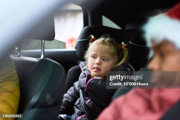 cute young girl with down syndrome and blonde hair in car seat wearing seatbelt - safe kids day arrivals stock pictures, royalty-free photos & images