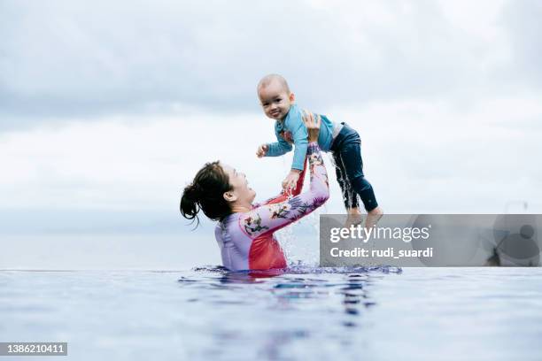 mother carrying baby during swimming on the pool - carrying water stock pictures, royalty-free photos & images