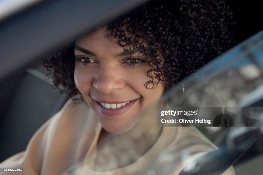 Side portrait of happy smiling young african american woman driving a car