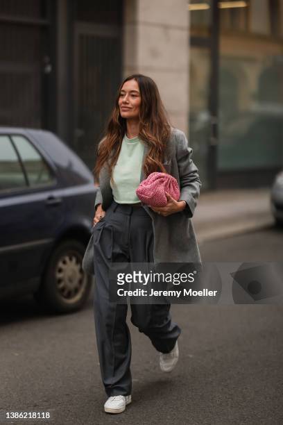 Anna Schürrle is wearing a grey oversized blazer, a green pullover, dark grey wide pants, white Celine sneaker and a pink mini clutch on March 17,...