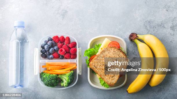 school lunch box with sandwich vegetables water almonds and fruits on - packed lunch - fotografias e filmes do acervo