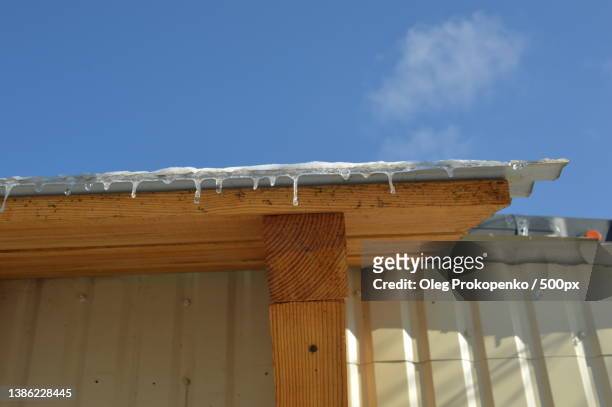 icicles of ice hang on the structure of the roof of the house - oleg prokopenko stock pictures, royalty-free photos & images