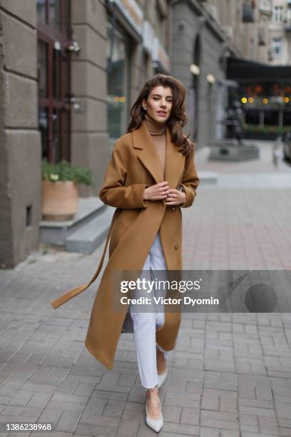 young model with long hair in light brown coat goes towards the camera. - duster stock pictures, royalty-free photos & images
