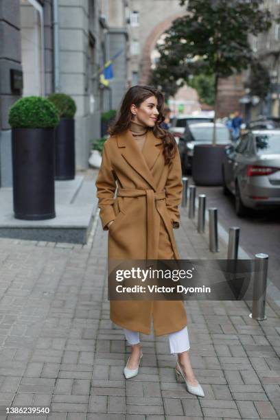 young model standing wearing light brown coat and smiling. - brown coats stockfoto's en -beelden