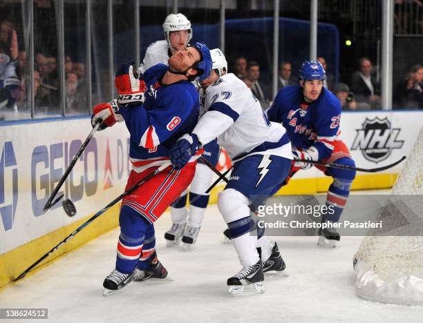 Brandon Prust of the New York Rangers reacts after being hit in the face by the puck as Bruno Gervais of the Tampa Bay Lightning reaches in during...