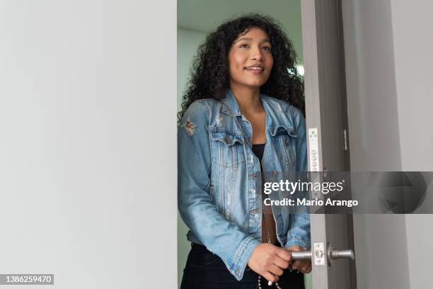 latin woman with curly hair is entering her apartment - woman entering home stock pictures, royalty-free photos & images