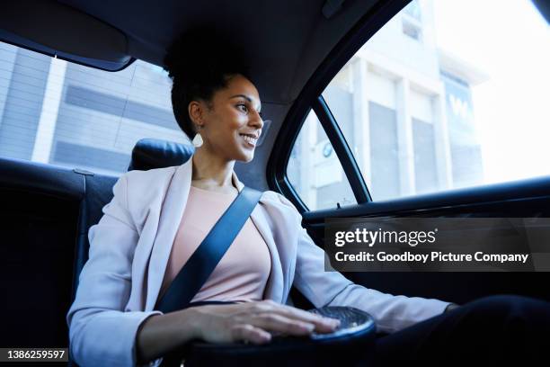 smiling businesswoman looking at the city from the back seat of taxi - driver rider stock pictures, royalty-free photos & images