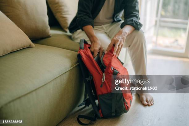 asian man packing backpack at home for journey in vacation day. - the weekend in news around the world stockfoto's en -beelden