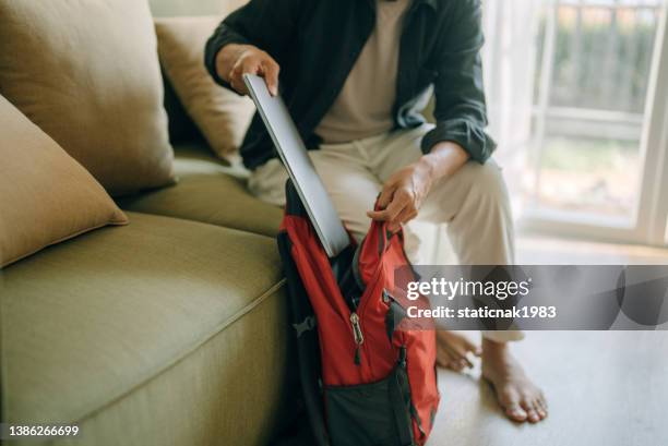 hombre asiático preparando mochila para el trabajo - mochila-bolsa fotografías e imágenes de stock