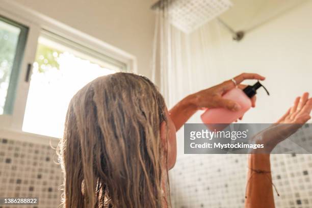 frau duscht und benutzt rosa conditioner - women haircare stock-fotos und bilder