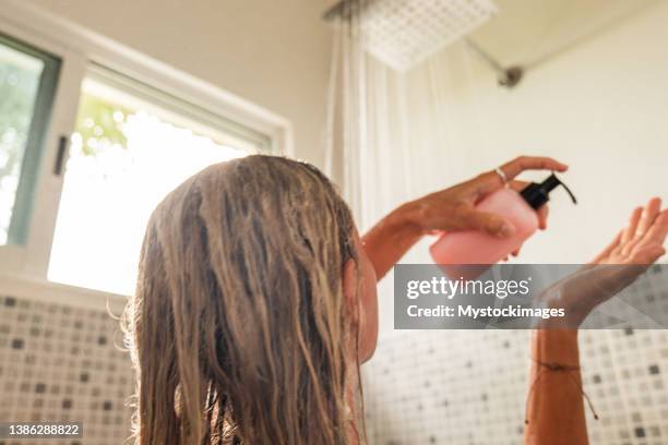 la femme prend une douche et utilise un revitalisant rose - se laver les cheveux photos et images de collection