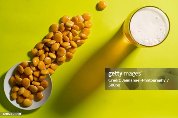 high angle view of beans with glass of beer on yellow background - cerveja stock pictures, royalty-free photos & images