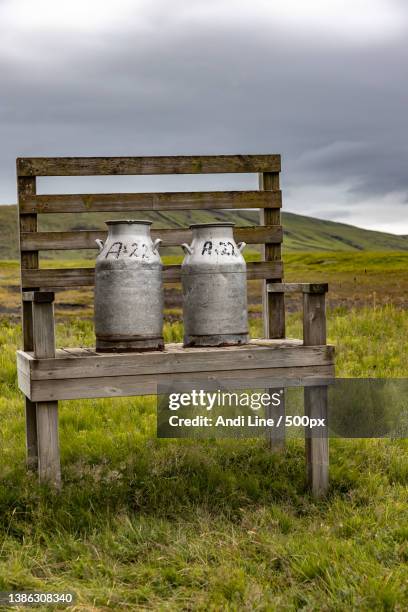 milk jugs on a wodden bench on a field - used milk cans stock pictures, royalty-free photos & images