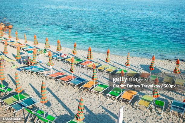 empty beach with closed umbrellas on italian coast - multi coloured umbrella stock pictures, royalty-free photos & images