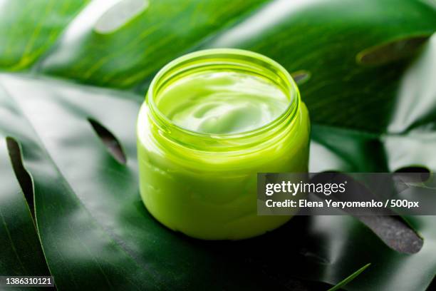 high angle view of green liquid cosmetic cream on green leaf in bottle on table - green room stockfoto's en -beelden