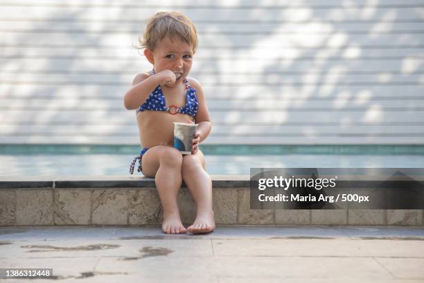 little girl eating yogurt by the pool - soft focus eye water stock-fotos und bilder