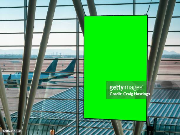 large green screen blank empty marketing billboard sign in airport departure lounge setting. chromakey with copy space perfect for vacation, holidays and tourism marketing. - airport poster stock-fotos und bilder