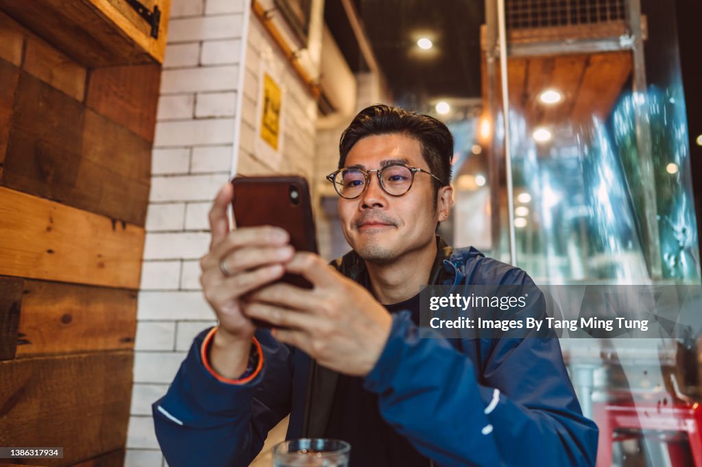 Young handsome Asian man making order from the digital menu on smartphone in restaurant