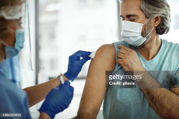 mid adult man receiving covid-19 vaccine. - receiving treatment concerned stock pictures, royalty-free photos & images