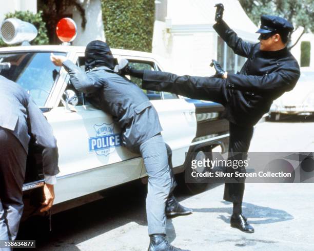 Bruce Lee , Chinese American actor and martial artist, kicks out at a criminal in a publicity portrait issued for the US television series, 'The...