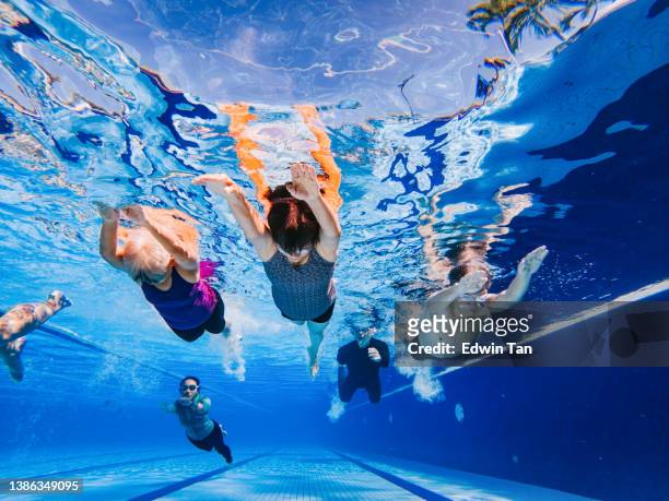 treinador chinês asiático assistindo seu aluno sênior nadando sob a água na piscina - natação - fotografias e filmes do acervo