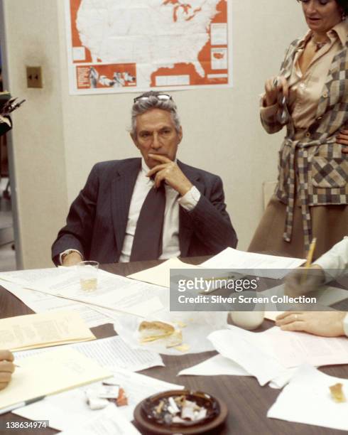 Peter Finch , British actor, sitting behind a desk, with a pensive expression on his face, in a publicity still issued for the film, 'Network', 1976....