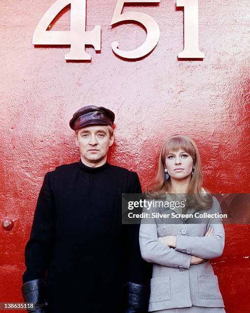 Oskar Werner , Austrian actor, and Julie Christie, British actress, pose beneath a large 451 sign, issued as publicity for the film, 'Fahrenheit...