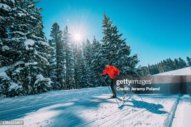 weitwinkelaufnahme eines langläufers beim skifahren in einer v1-formation entlang einer präparierten loipe an einem klaren, sonnigen tag im grand mesa national forest in colorado - langlaufen stock-fotos und bilder