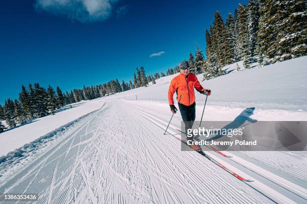 alegre esquiador de fondo esquiando a lo largo de un sendero arreglado en un día claro y soleado de "pájaro azul" en el bosque nacional grand mesa en colorado - esquíes de fondo fotografías e imágenes de stock
